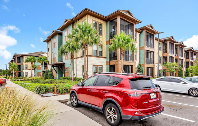 a red car parked in front of an apartment complex