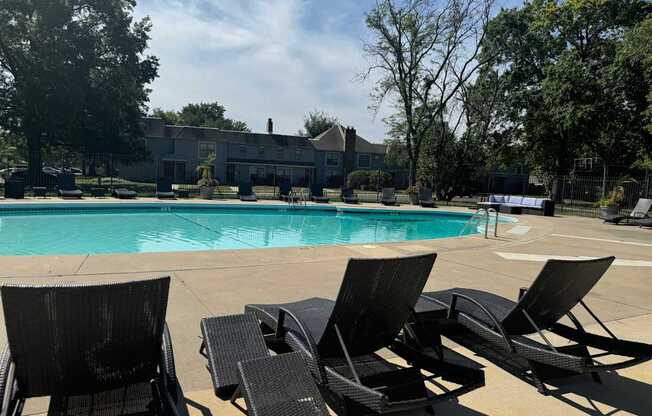 A pool surrounded by trees and chairs.