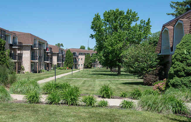 a yard with grass and trees in front of apartment buildings