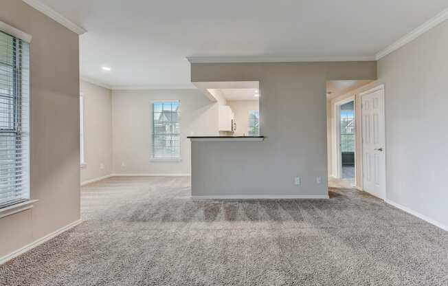 an empty living room with carpet and a kitchen