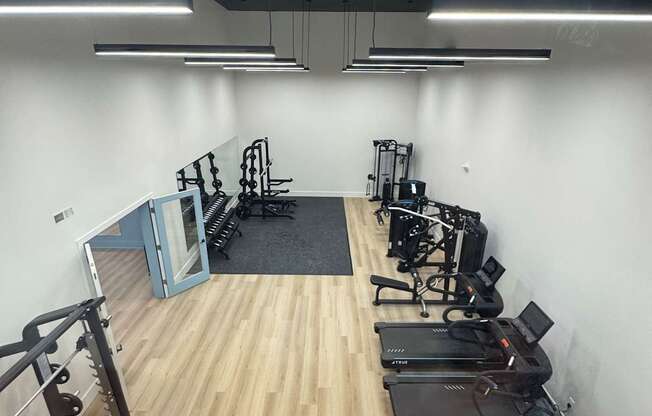 A room with a wooden floor and a white wall with a TV and a chair.