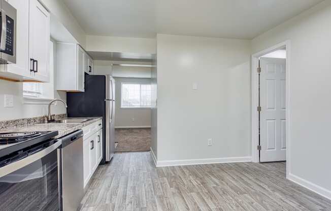 an empty kitchen with white cabinets and stainless steel appliances