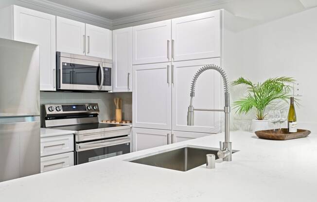 a white kitchen with stainless steel appliances and a sink