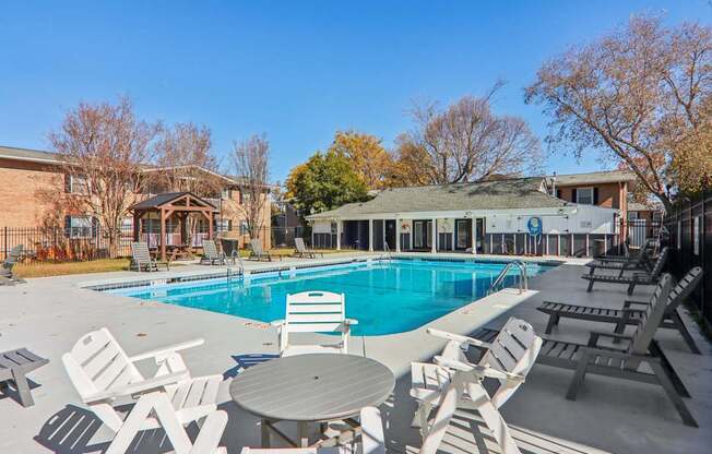 A pool surrounded by chairs and tables.