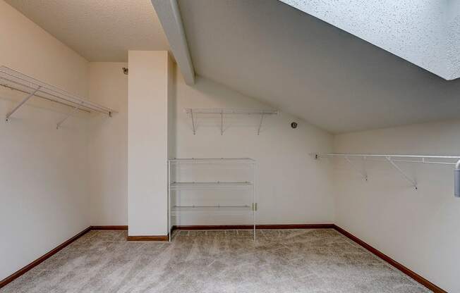 an empty room with white walls and a closet with shelves