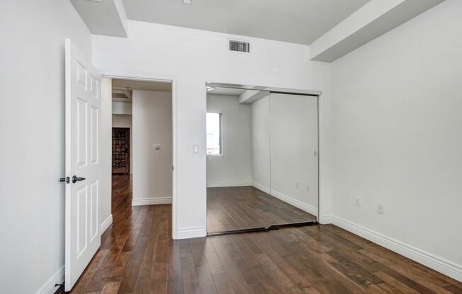 a bedroom with hardwood floors and white walls