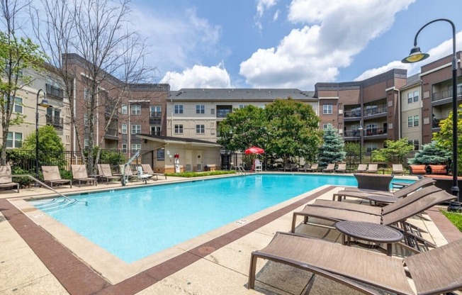 A large swimming pool surrounded by lounge chairs and umbrellas in a sunny day.