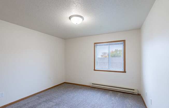 the living room of an empty house with a window. Fargo, ND Oxford Apartments