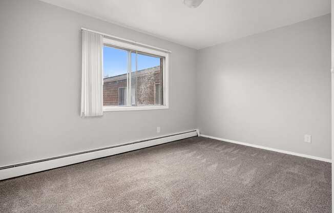 A room with a large window and a carpeted floor.