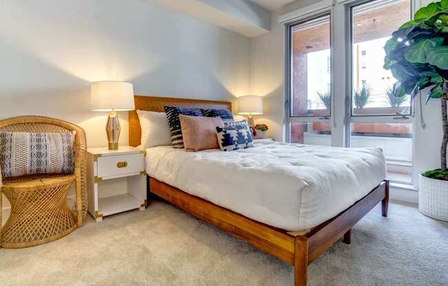 A bedroom with a bed, chair, and potted plant.