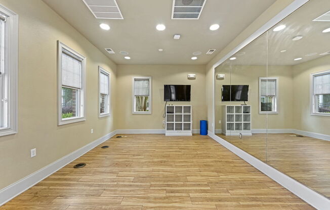 large fitness studio with full wall mirror, tv, and ample space for yoga, dance, or stretching