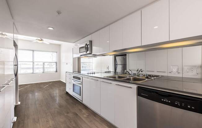 A modern kitchen with white cabinets and stainless steel appliances.