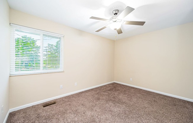 an empty room with a window and a ceiling fan