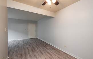 A room with a white door and a brown floor.