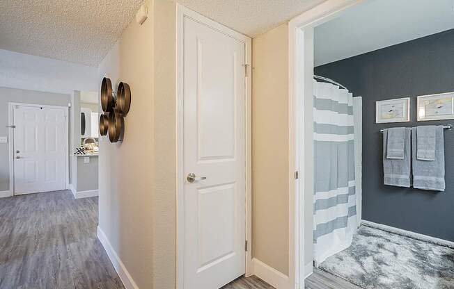 A hallway with a white door and a wall with three clocks on it at Sterling Point Apartment Homes, Phoenix, AZ