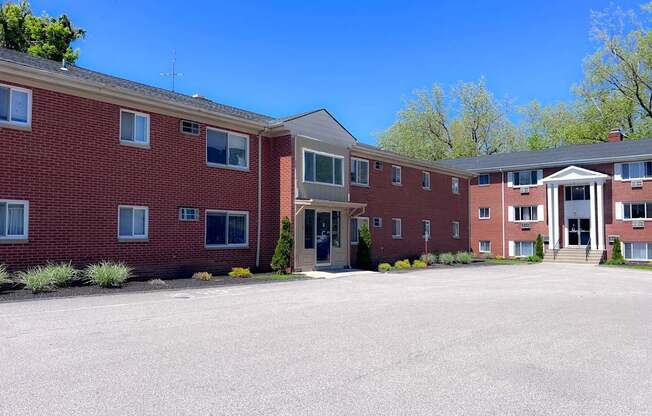 A large red brick building with a parking lot in front.