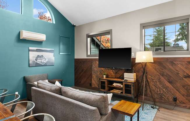 A living room with a grey couch, a wooden side table, and a television.