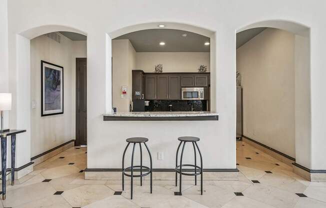 A kitchen area with a bar counter and two stools.