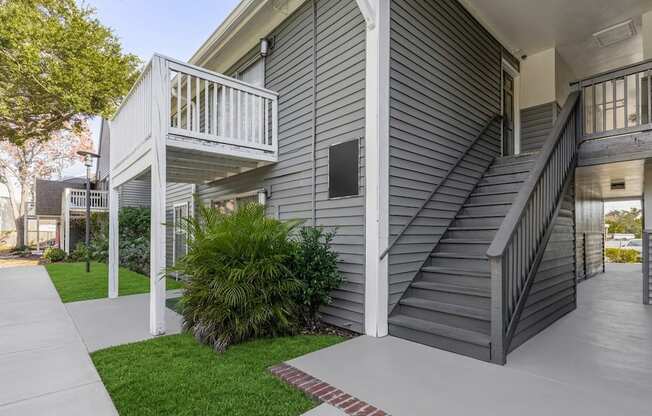 A grey house with a white balcony and stairs.