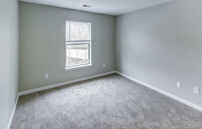 an empty room with carpet and a window