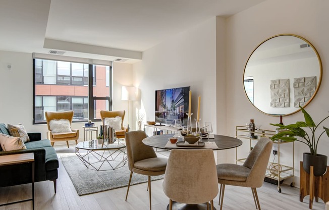 a living room with a round table with chairs and a large mirror on the wall