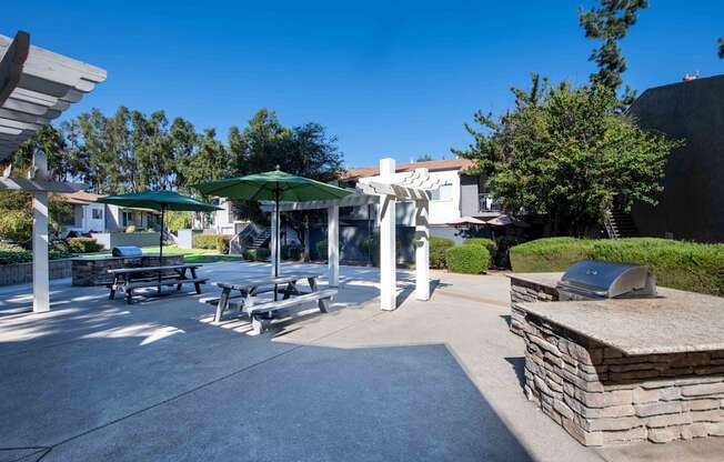 A sunny day at the park with a picnic table and umbrellas.