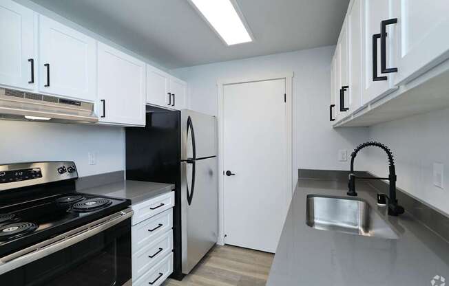 A kitchen with black appliances and white cabinets.