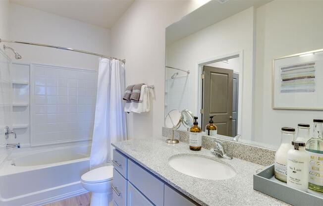 Bathroom with wide granite countertop, toilet, and full tub and shower at The Station at Savannah Quarters apartments for rent in Pooler, GA