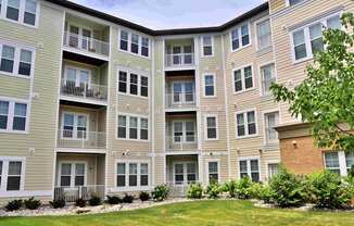 an exterior view of an apartment building with a green yard