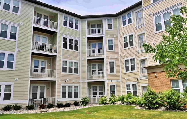 an exterior view of an apartment building with a green yard