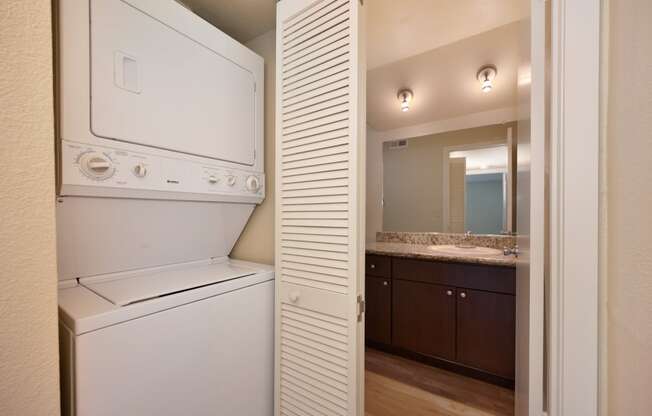 Hallway area with washer and dryer in a closet with accordion style door and views of the bathroom