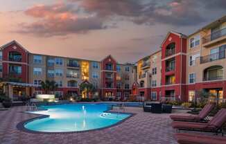 a swimming pool in front of an apartment building at sunset