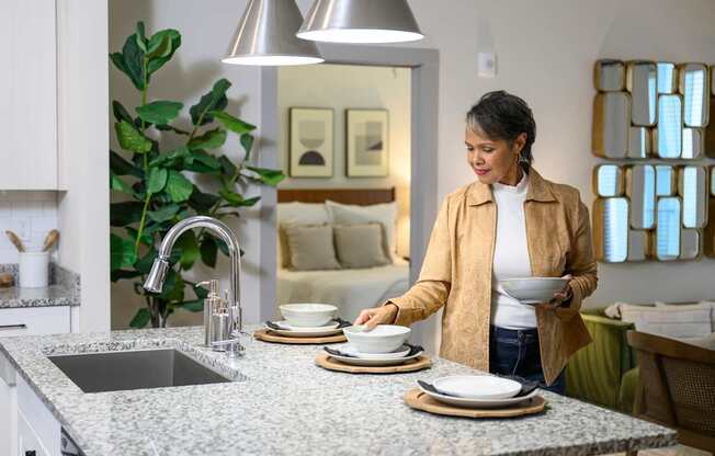 a woman placing dishes on a counter in a kitchen