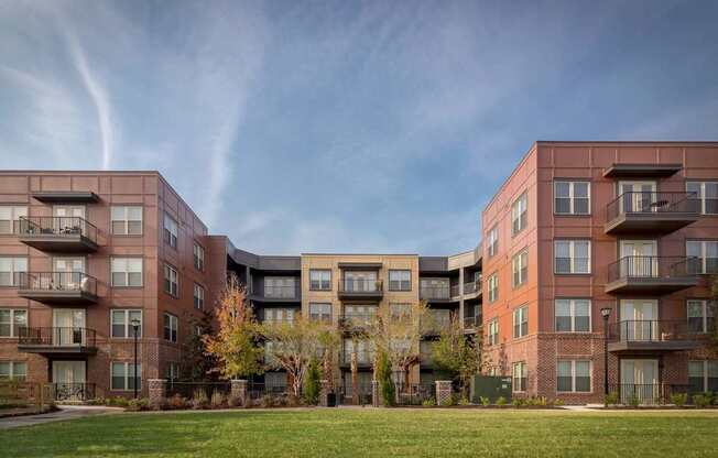 A large apartment complex with multiple balconies and trees in the front yard.