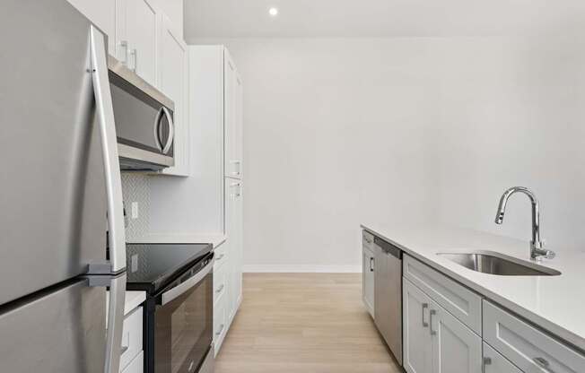 A modern kitchen with a refrigerator, oven, and sink.