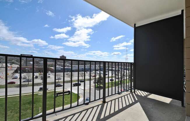 A balcony with a black railing overlooks a parking lot.