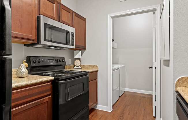 a kitchen with black appliances and wooden cabinets and a white door