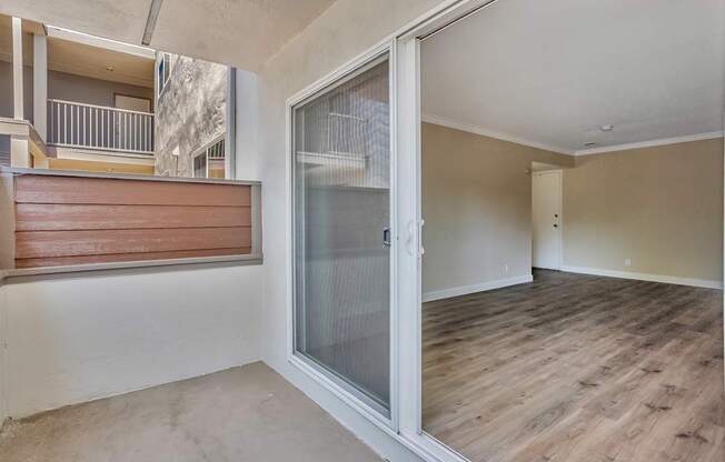 A room with a sliding glass door and wooden flooring.