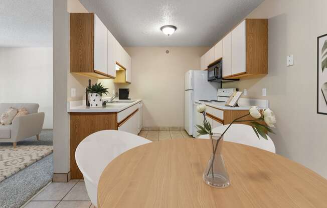 a dining room table with a vase of flowers and a kitchen and living room