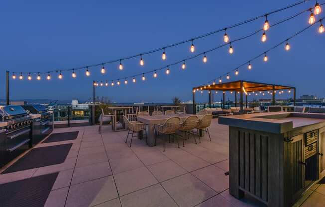 a rooftop terrace with tables and chairs and string lights