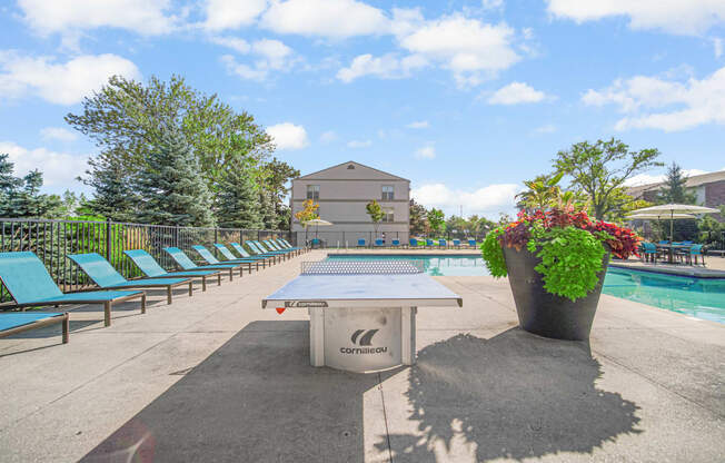 a pool with a ping pong table and chairs next to a pool