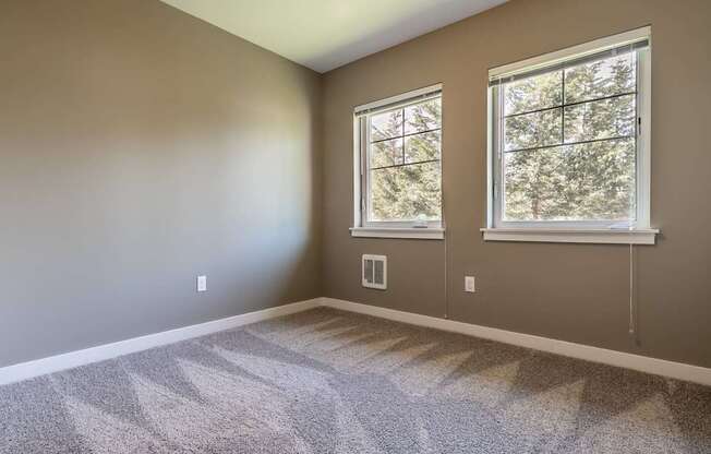 A room with two windows and carpeted floor.