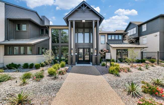 the front entrance of a house with a gravel pathway and plants