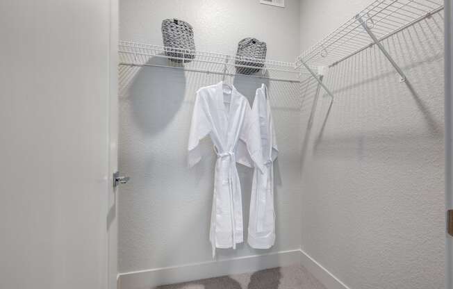 a walk in closet with two white robes hanging on a rack