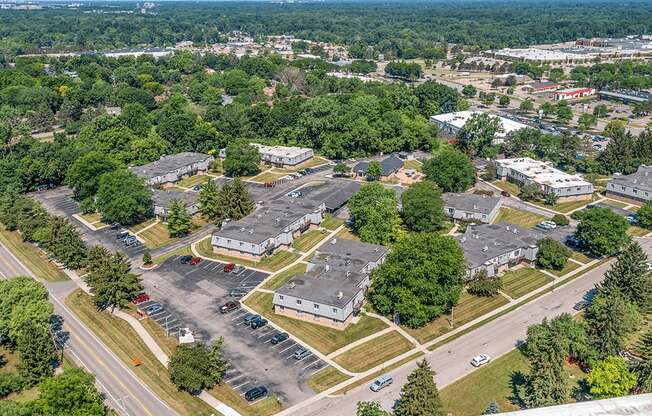 A bird's eye view of a parking lot surrounded by buildings and trees.