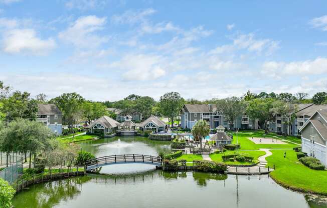 an aerial view of a lake with a bridge and houses in the background