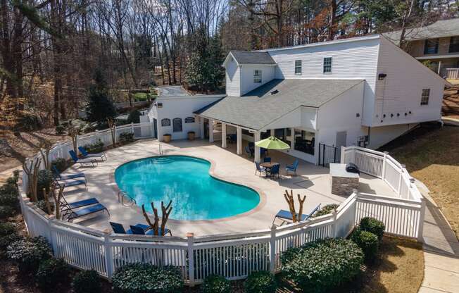 a backyard with a pool and a house with a white fence around it