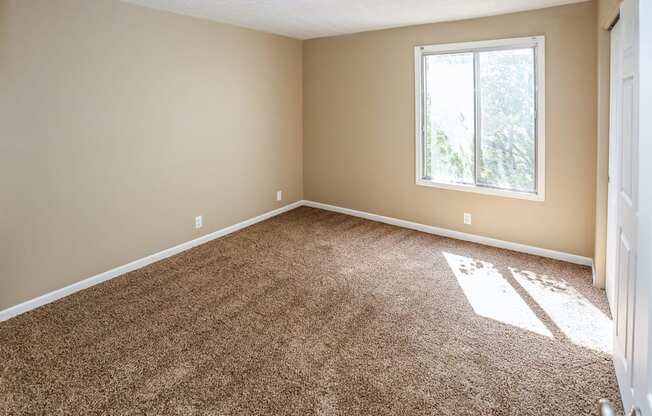 an empty room with carpet and a window. Omaha, NE Evergreen Terrace Apartments