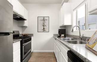 A modern kitchen with a stove, sink, and cabinets.