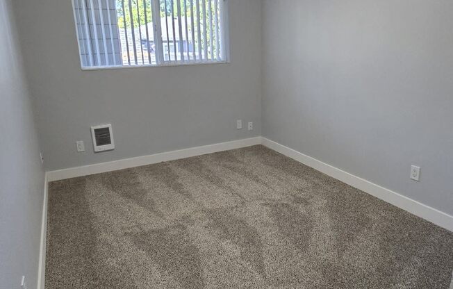 an empty bedroom with ceiling light and single window